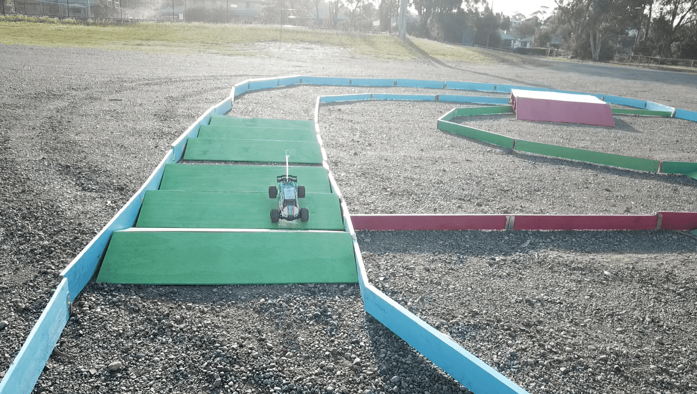 Multiple kids racing RC cars in enclosed arena